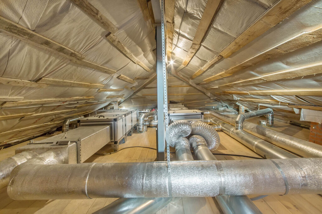 Whole house air ventilation and cleaning system. Ventilation pipes in silver insulation material on the attic